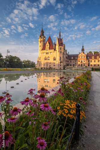 Obraz na płótnie Majestic Moszna Castle on a warm summer morning, surrounded by lush greenery and glowing in soft golden sunlight, reflecting a fairytale-like ambiance perfect for travel and architecture themes. w salonie
