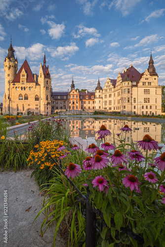 Obraz na płótnie Majestic Moszna Castle on a warm summer morning, surrounded by lush greenery and glowing in soft golden sunlight, reflecting a fairytale-like ambiance perfect for travel and architecture themes. w salonie