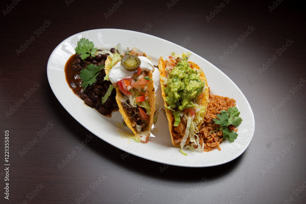 Mexican food platter displaying colorful tacos, garnished with fresh ingredients, served alongside seasoned rice and black beans Mexican food platter displaying colorful tacos, garnished with fresh ingredients, served alongside seasoned rice and black beans