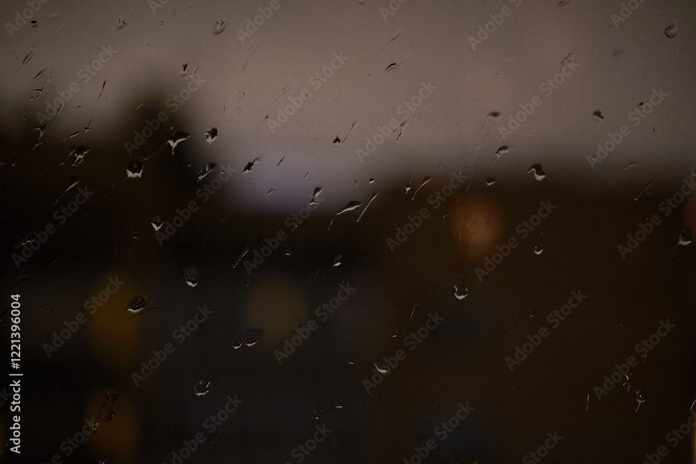 Obraz premium Evening landscape. Water Drops on Rain window glass .Transparent Glass in rainy day. View of city from the window.