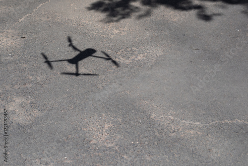 A sharp drone shadow contrasts against the rough texture of the asphalt.
A drone's shadow casts a haunting figure on a cracked asphalt .