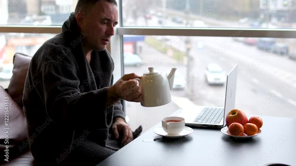 a man in a robe drinks tea after a bath Sleepy casual young man wearing bathrobe drinking a cup of coffee or tea in the morning switching tv channels isolated on white background. a man in a robe drinks tea after a bath Sleepy casual young man wearing bathrobe drinking a cup of coffee or tea in the morning switching tv channels isolated on white background.