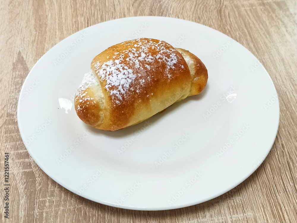 Freshly baked pastry sits on a white plate on a wooden table Freshly baked pastry sits on a white plate on a wooden table