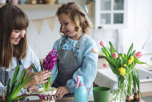 Spring home gardening concept. Little cute girl and her mother planting bulb flowers in the kitchen. Eco friendly leisure time, hobby, recreation. Earth day, ecology project for school photo