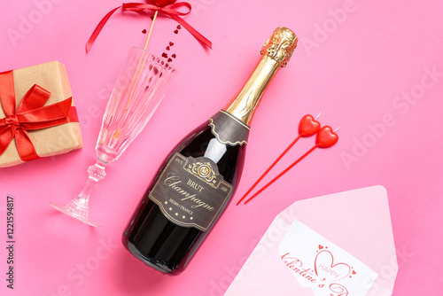 Bottle of champagne with glass, gift box and decor on pink background. Valentine's Day celebration