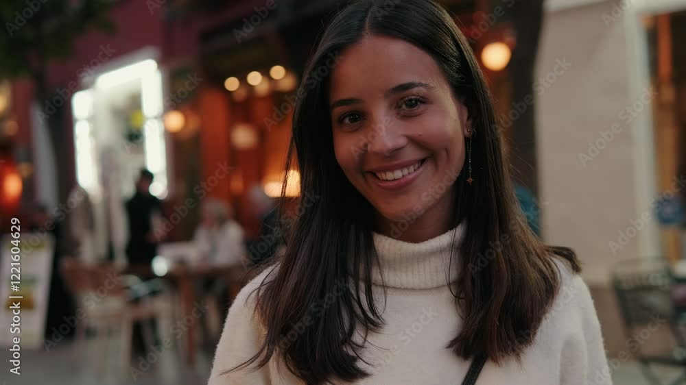 Portrait of a young woman smiling at the camera in Seville, Spain. She wears a white sweater and has long brown hair. Portrait of a young woman smiling at the camera in Seville, Spain. She wears a white sweater and has long brown hair.