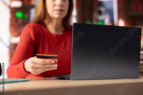 Responsible adult at home office organizing family finances on laptop, tracking joint account expenses by entering card numbers online. Woman confirming money transfer for her children. photo