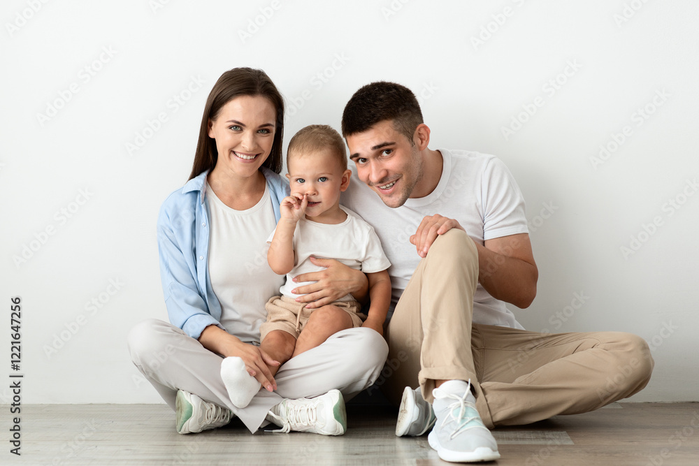 Portrait Of Beautiful Young Happy Family With Infant Child Posing At Home, Millennial Mother And Father And Their Cute Toddler Baby Sitting On Floor, Embracing And Smiling At Camera, Free Space Portrait Of Beautiful Young Happy Family With Infant Child Posing At Home, Millennial Mother And Father And Their Cute Toddler Baby Sitting On Floor, Embracing And Smiling At Camera, Free Space