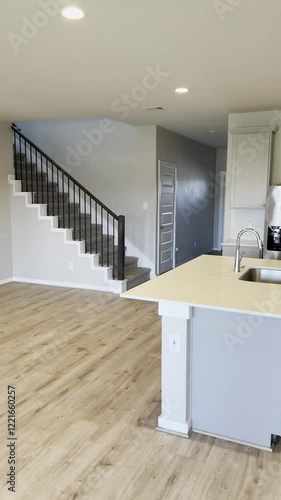 Empty modern open concept kitchen interior with dining room, white countertops, with stainless steel stove, microwave, refrigerator, dishwasher appliances and wood floors. 