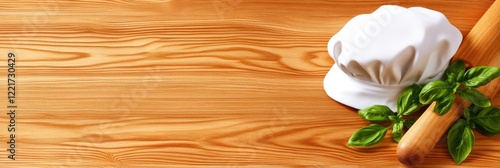 Chef hat and rolling pin on wooden table with fresh basil leaves photo