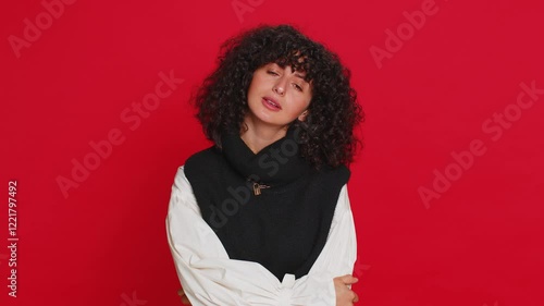 Caucasian young woman with curly hair tired bored indifferent expression, exhausted of tedious story, not interested in communication talk, displeasure, uninteresting. Girl isolated on red background