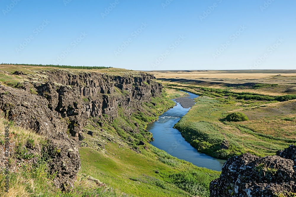 Serene river winding through lush green landscape with rocky cliffs under clear blue sky Serene river winding through lush green landscape with rocky cliffs under clear blue sky