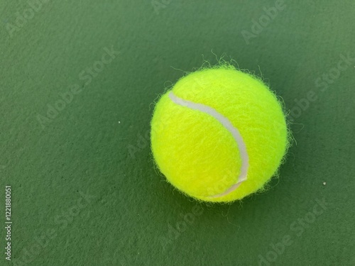 Very close-up shot of a single green tennis ball placed on a green tennis court
