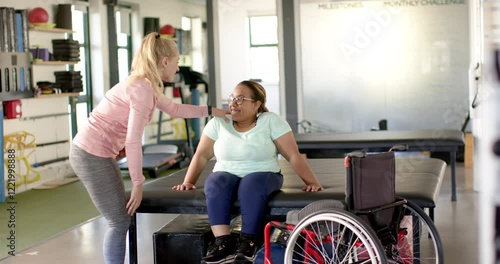 Assisting woman with paraplegia in wheelchair, physical therapist during rehabilitation session
