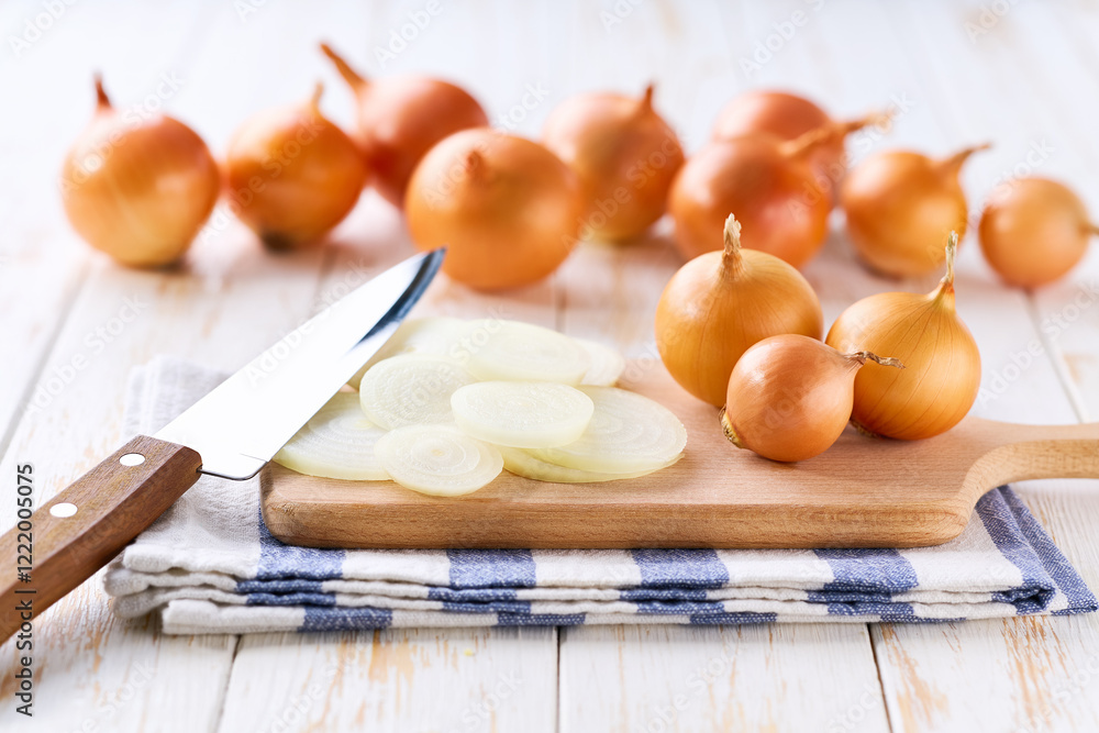 Sliced yellow onions in a cutting board on a light kitchen table. Sliced yellow onions in a cutting board on a light kitchen table.