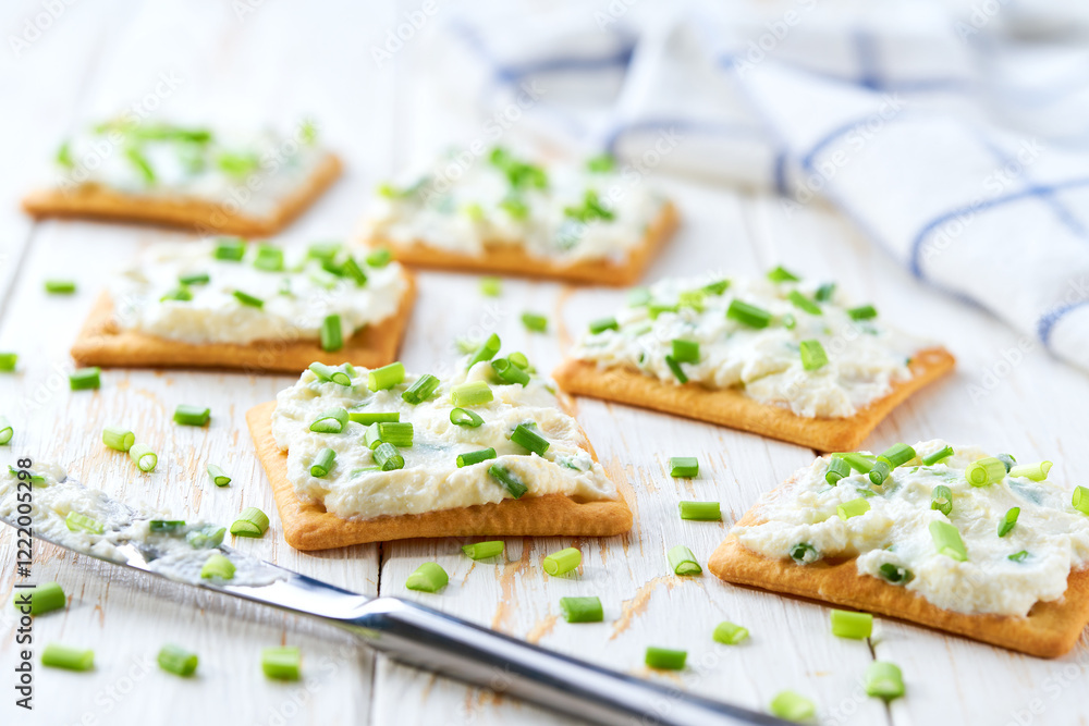 light snack of crackers with cream cheese and green onion on a blue napkin. light snack of crackers with cream cheese and green onion on a blue napkin.