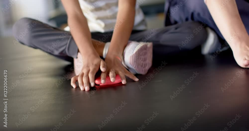 Girl with cerebral palsy in disability rehab stretching hands on floor during therapy session Girl with cerebral palsy in disability rehab stretching hands on floor during therapy session