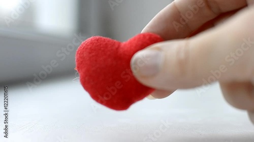 Red heart in woman's hand on grey background. The concept of charity, love, donate and helping hand. International cardiology day. A woman gives a red heart to the man's hands