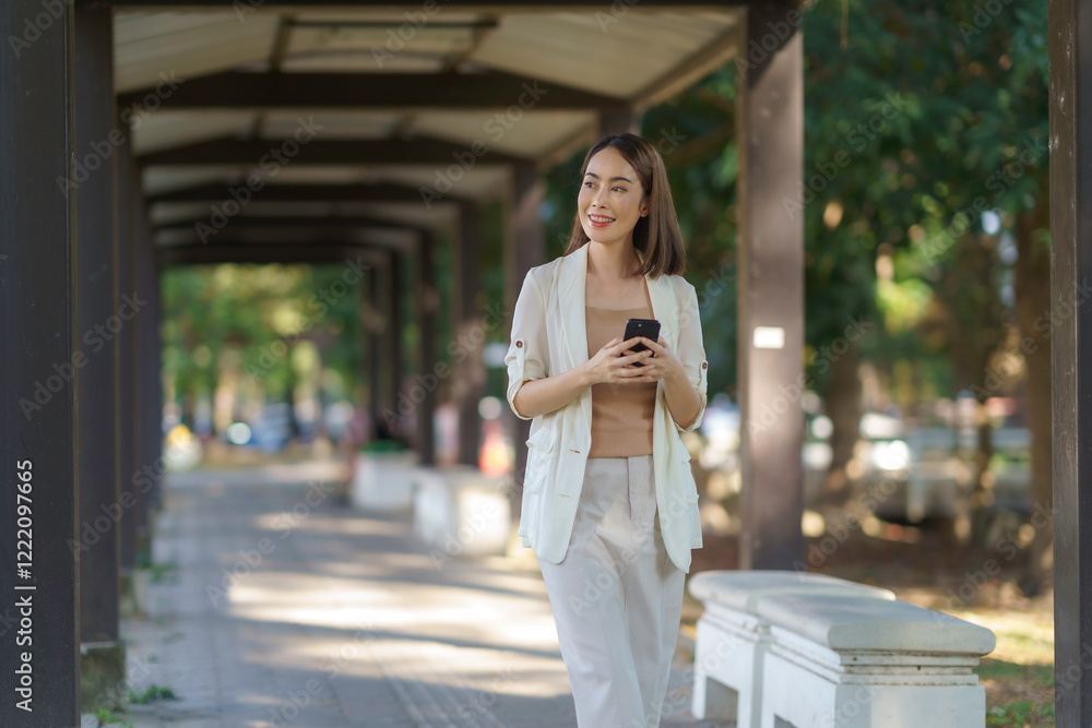 Businesswoman walking and using smartphone under walkway in the city Businesswoman walking and using smartphone under walkway in the city