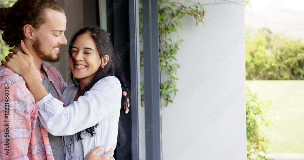 Biracial woman and Caucasian man laughing by window, embracing, copy space Biracial woman and Caucasian man laughing by window, embracing, copy space