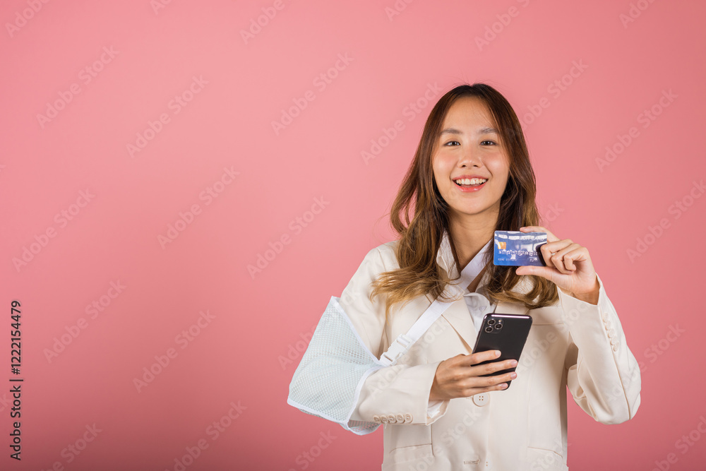 Woman confident smile broken arm after accident and wear arm splint for treatment she emergency pay medical bills by credit card and mobile phone, Asian female sling support hand isolated background Woman confident smile broken arm after accident and wear arm splint for treatment she emergency pay medical bills by credit card and mobile phone, Asian female sling support hand isolated background