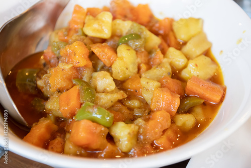 Colorful vegetable stew in a bowl. Aloo Matar is a delicious North Pakistan curry made with potatoes, peas, onions, tomatoes, spices and herbs. photo