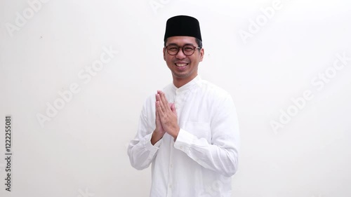 A muslim man smiling happy doing greeting pose with hand praying gesture