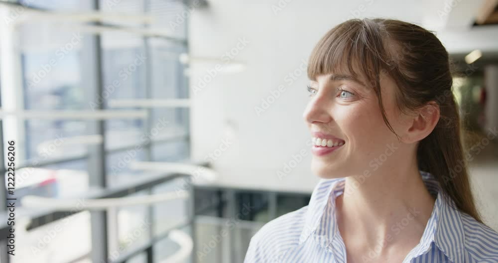 Smiling woman looking out window in modern office building, feeling inspired Smiling woman looking out window in modern office building, feeling inspired