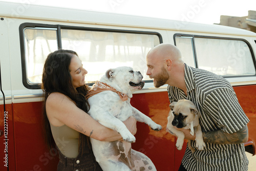 Happy couple bonding with their adorable dogs near a vintage red van. photo