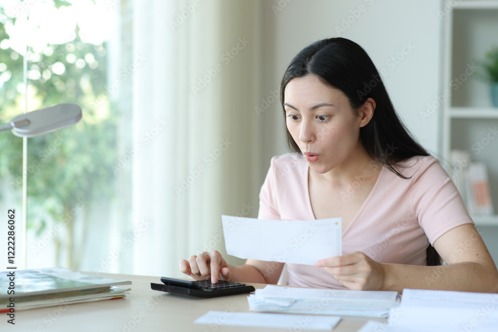 Surprised asian woman calculating expenses at home Surprised asian woman calculating expenses at home