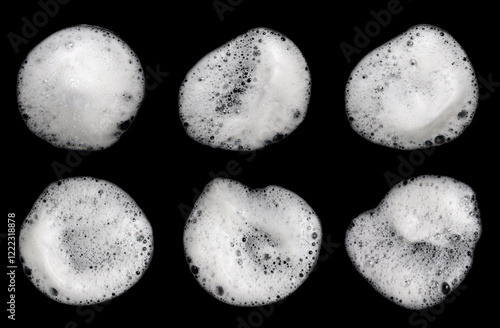 Liquid white foam from soap, shampoo or bath foam. Abstract soap bubbles. Set of soap bubbles. Separated soap bubbles on black background with contrasting texture.
