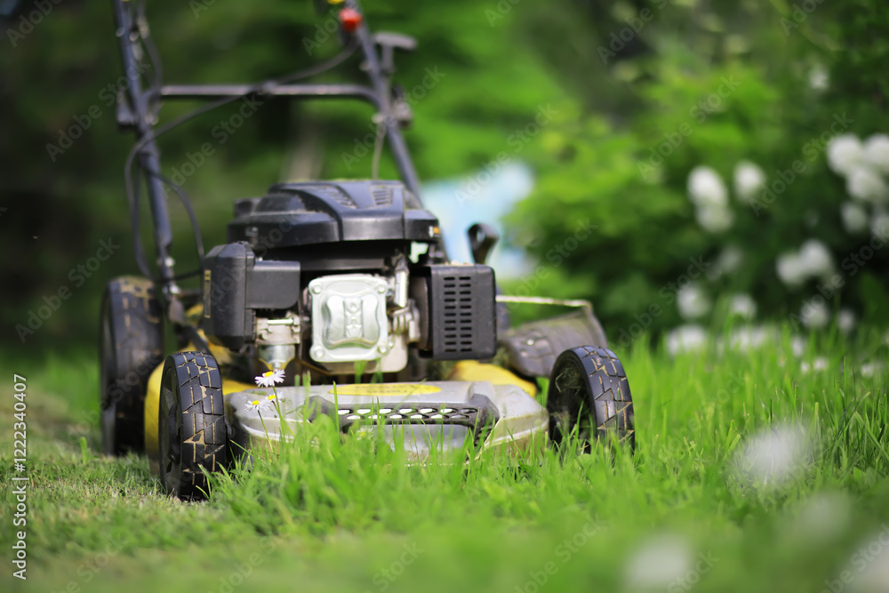 Lawn mover on green grass in modern garden. Machine for cutting lawns. Lawn mover on green grass in modern garden. Machine for cutting lawns.