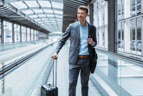 Businessman with baggage on moving walkway photo