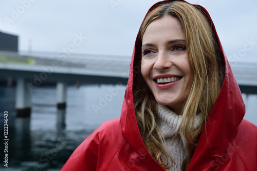 Denmark, Copenhagen, portrait of happy woman at the waterfront in rainy weather photo