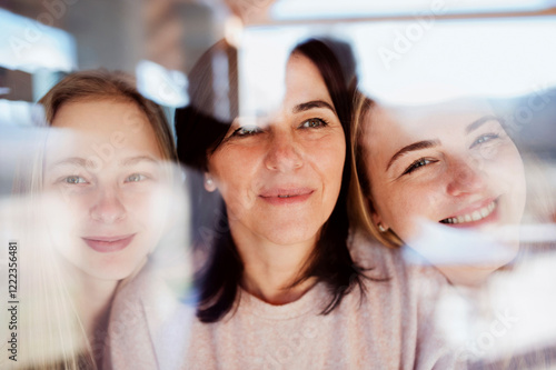 Visiting daughters embracing their mother, standing at the window photo