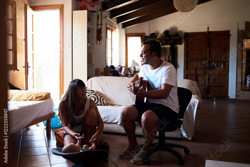 Father playing guitar and mother playing with little boy at home photo