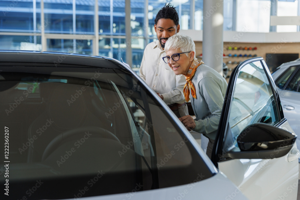 Salesperson showing car to customer in showroom Salesperson showing car to customer in showroom