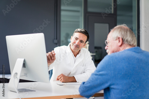 Doctor sharing computer screen with patient in medical practice photo