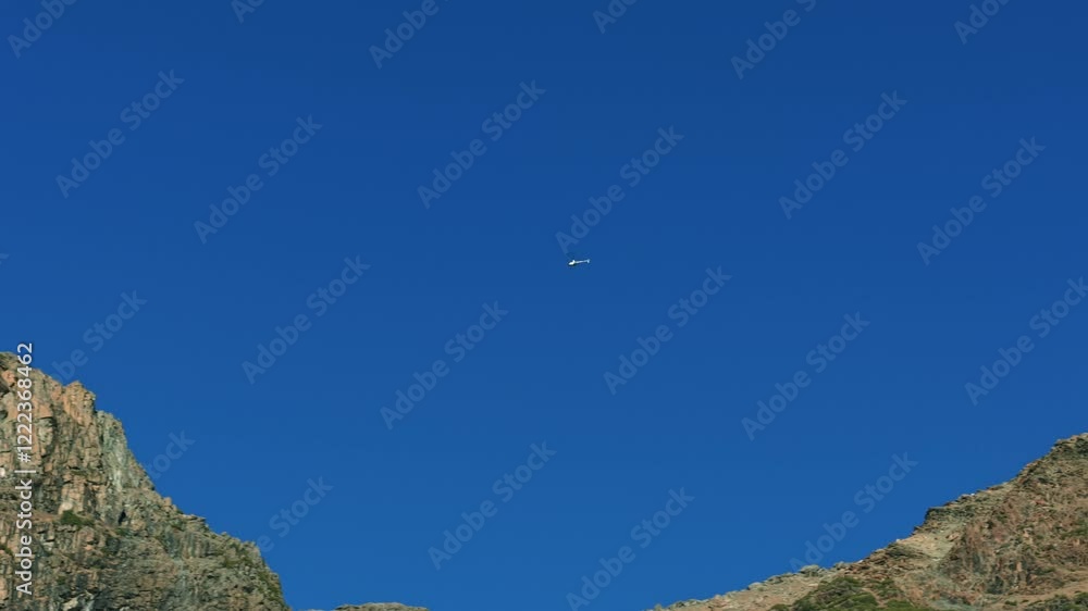 Helicopter flies over mountains, clear and blue sky, copy space Helicopter flies over mountains, clear and blue sky, copy space