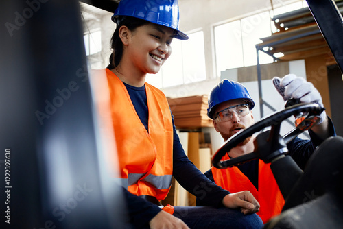 Man instructing female worker on forklift in factory