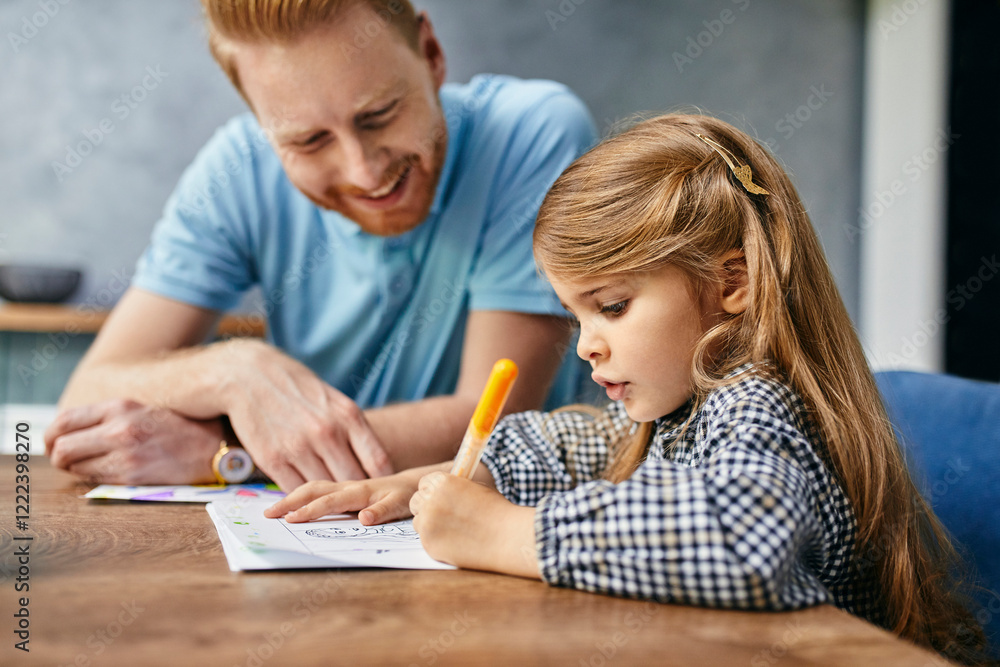 Father and daughter sitting at table, painting colouring book Father and daughter sitting at table, painting colouring book