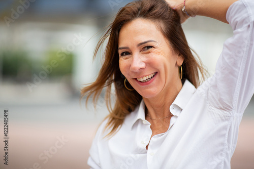 cheerful portrait of a woman in a casual moment, captured while she adjusts her hair.