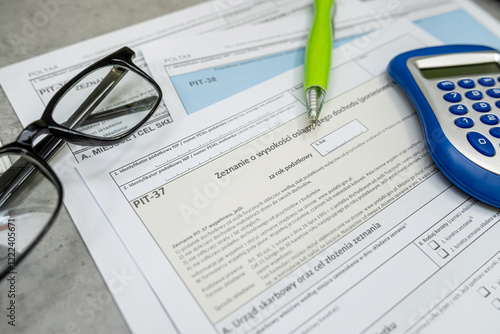 Polish tax form PIT-38, PIT-37 PIT-36L pen calculator glasses on desk. Lump sum recorded on revenues photo