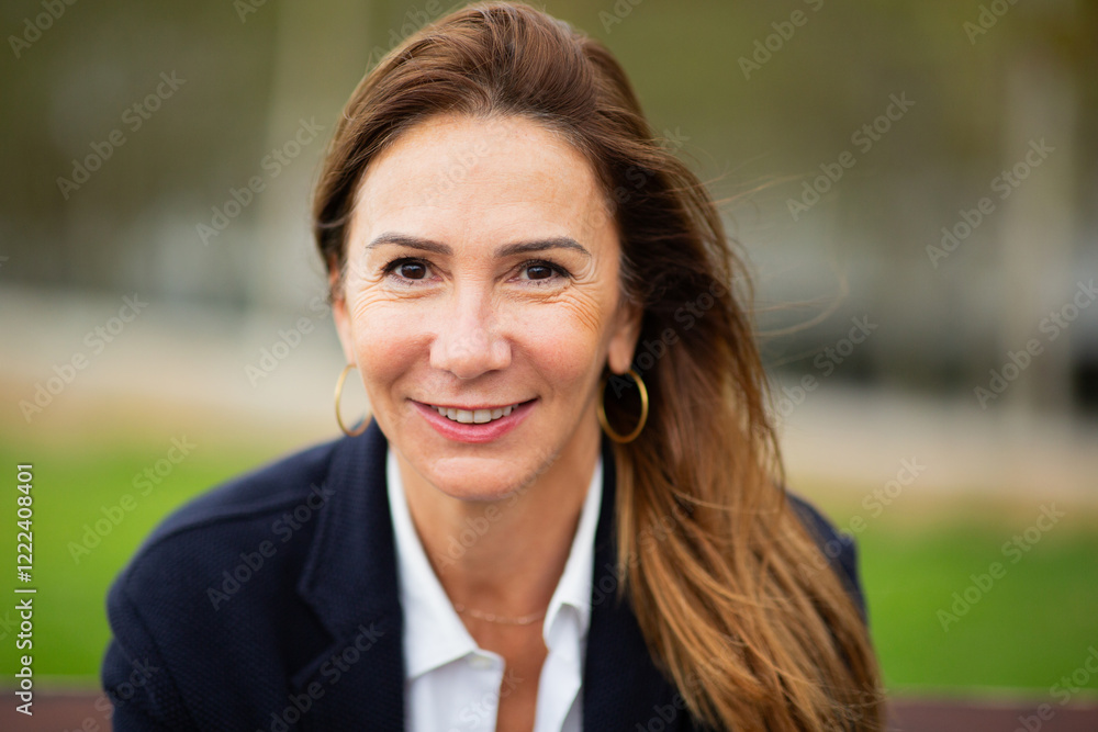confident woman with a warm smile, set against an outdoor background. confident woman with a warm smile, set against an outdoor background.