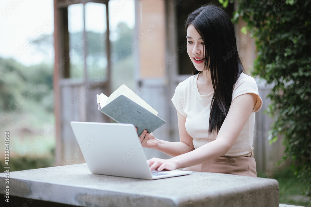 A confident young Asian woman is working on her laptop in a vibrant park. E-banking and career aspirations in a modern lifestyle. A confident young Asian woman is working on her laptop in a vibrant park. E-banking and career aspirations in a modern lifestyle.