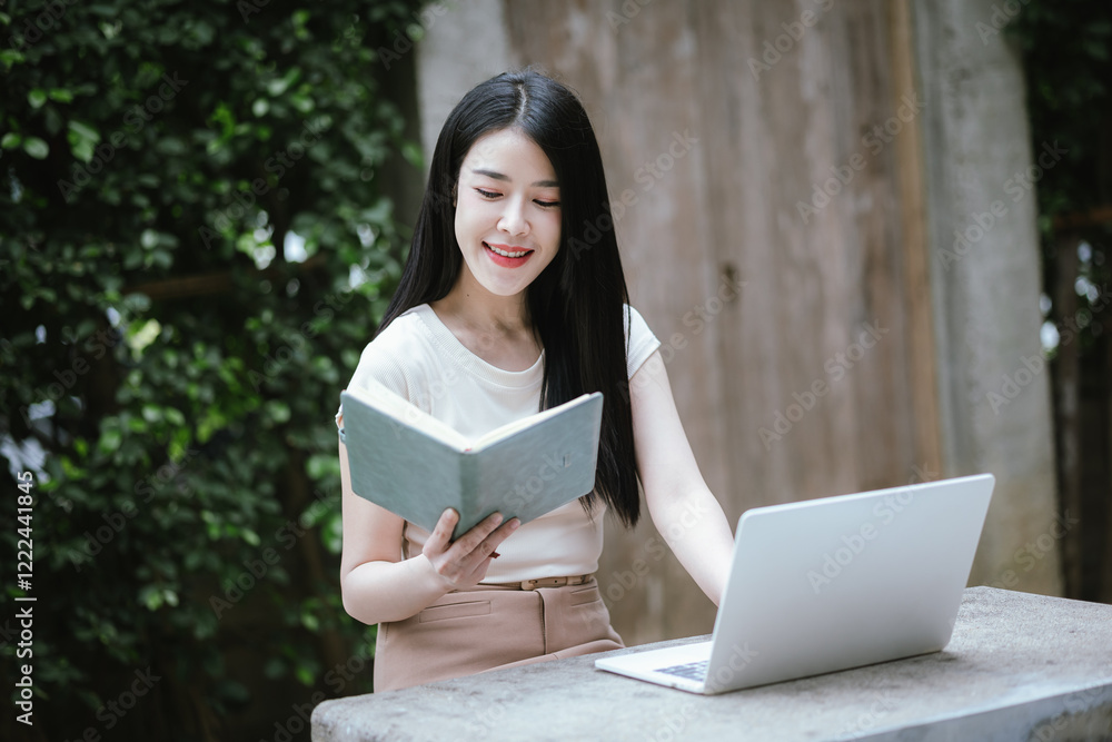 Obraz premium A confident young Asian woman is working on her laptop in a vibrant park. E-banking and career aspirations in a modern lifestyle.