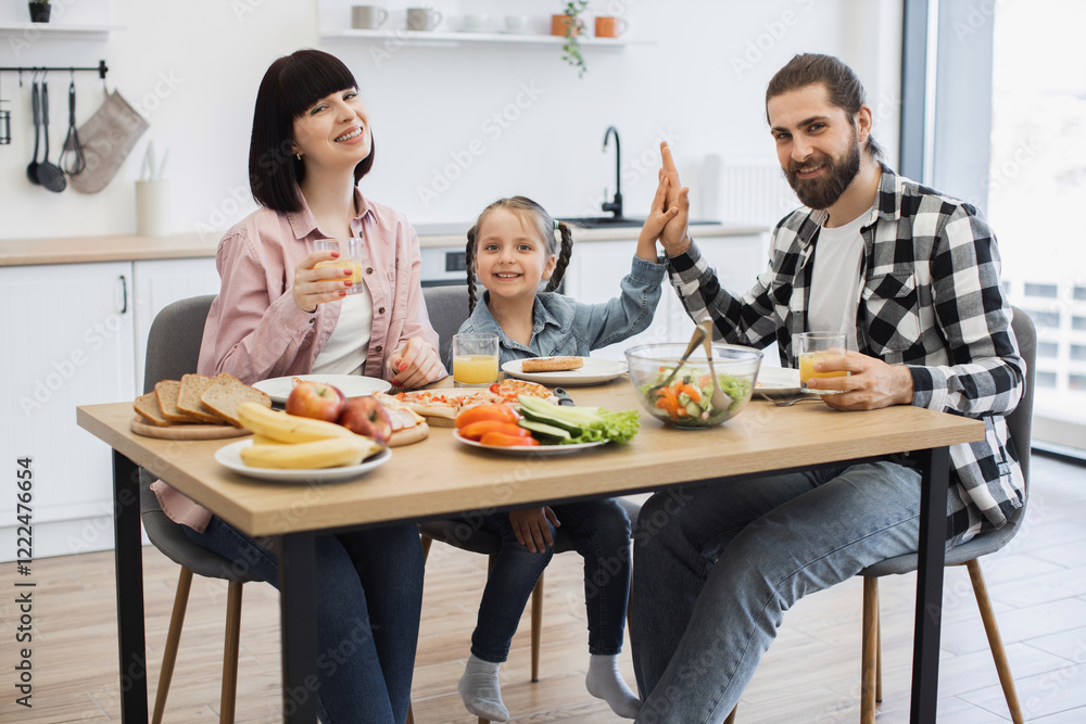 © sofiko14 - Caucasian family of three enjoying breakfast at home. Young daughter gives high five to father. Bright morning scene with happiness and togetherness. © sofiko14 - Caucasian family of three enjoying breakfast at home. Young daughter gives high five to father. Bright morning scene with happiness and togetherness.