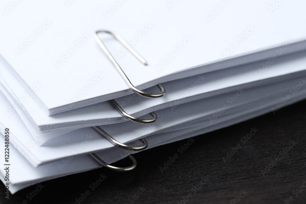 Paper notes with metal clips on black wooden table, closeup Paper notes with metal clips on black wooden table, closeup