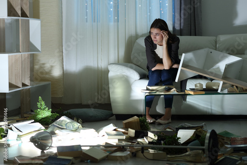 Фотография Sad woman complaining alone in the night after robbery at home
