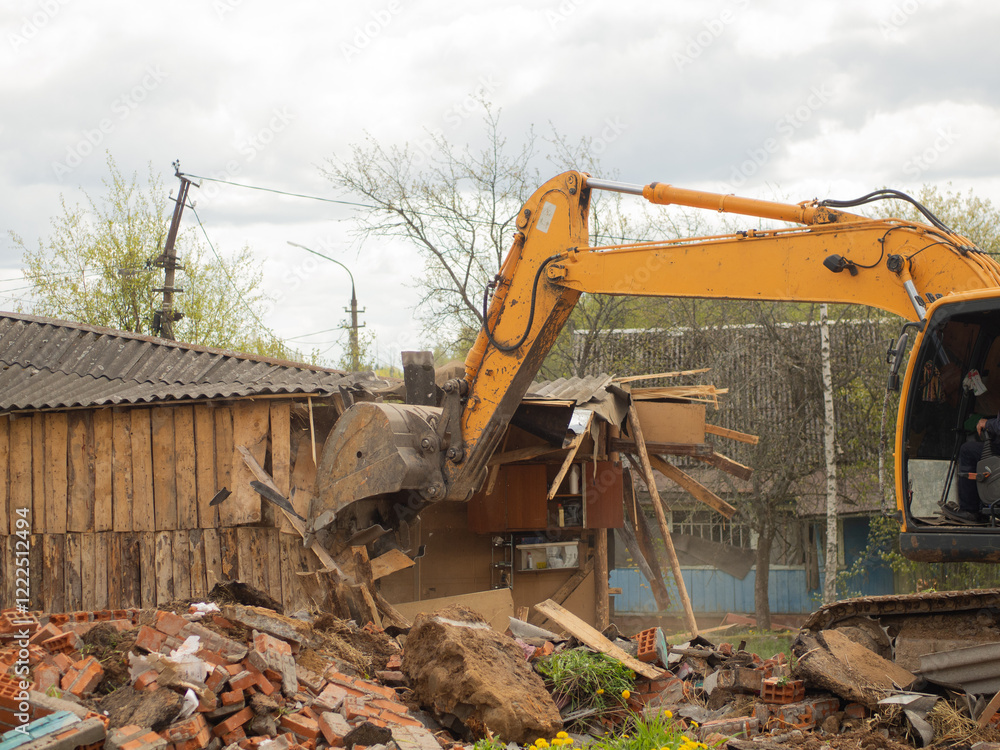Fototapeta premium yellow excavator demolishes old buildings with its bucket